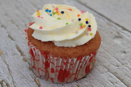 Sweet cake with tutti frutti sprinkles on top on the wooden table white background.の写真素材