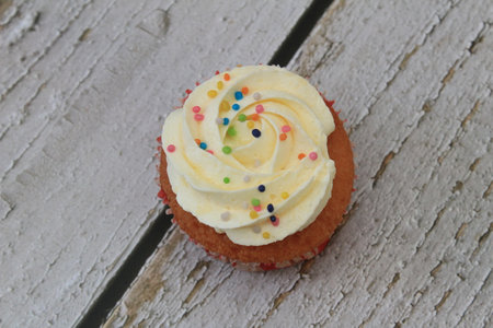 Sweet cake with tutti frutti sprinkles on top on the wooden table white background.の写真素材