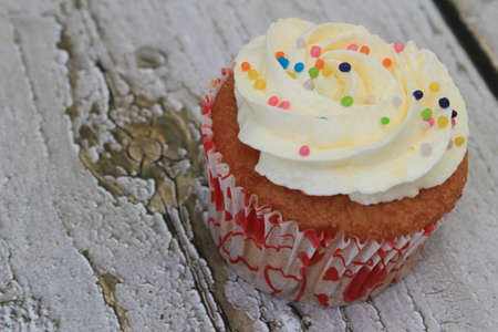 Sweet cake with tutti frutti sprinkles on top on the wooden table white background.の写真素材