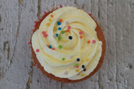 Sweet cake with tutti frutti sprinkles on top on the wooden table white background.の写真素材