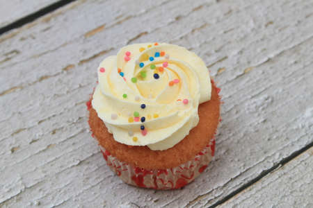 Sweet cake with tutti frutti sprinkles on top on the wooden table white background.の写真素材