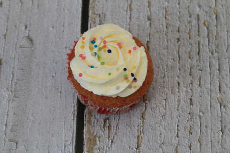 Sweet cake with tutti frutti sprinkles on top on the wooden table white background.の写真素材