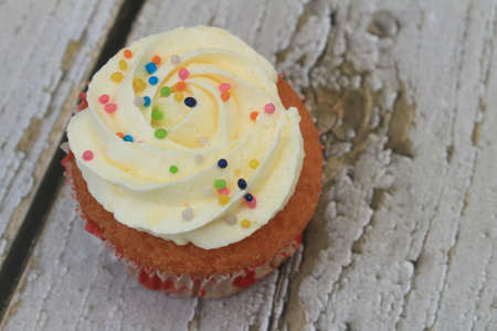 Sweet cake with tutti frutti sprinkles on top on the wooden table white background.の写真素材