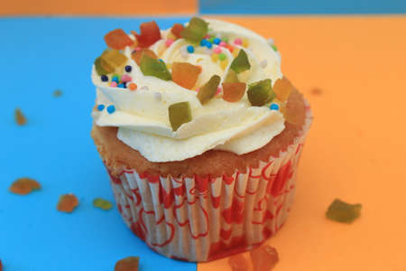 Sweet cake with tutti frutti sprinkles on top on the color background.の写真素材