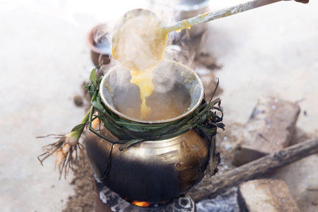 celebrating Traditional Pongal festival to sun god with pot, lamp,wood fire stove, fruits and sugarcane. Making Sakkarai or sugar pongal and ven pongal in sand stove in traditional method.の写真素材