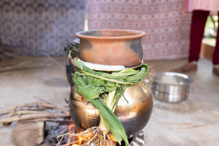celebrating Traditional Pongal festival to sun god with pot, lamp,wood fire stove, fruits and sugarcane. Making Sakkarai or sugar pongal and ven pongal in sand stove in traditional method.の写真素材