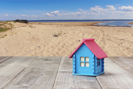 A small wooden house on a background of summer beach. Sandy coast, the sea and the layout of the houses on the shore.の写真素材