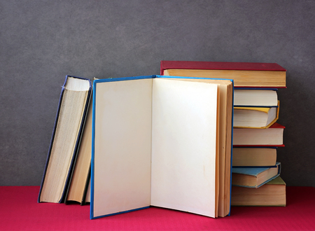 Stack of books in the colored covers on the table with a red tablecloth. Still life with books.の写真素材