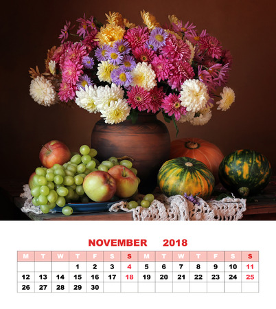 Page design calendar, November 2018. Autumn still life with a bouquet of chrysanthemums, green grapes, apples and pumpkins against a dark background.の写真素材