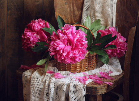 Retro still life with pink peonies crumbling. The flowers in the basket.の写真素材