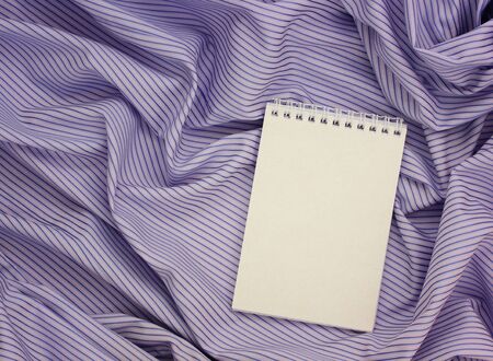 paper notebook with an empty cover on a purple-striped tablecloth. the view from the top. template,...