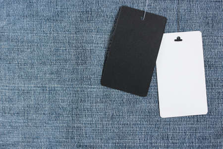 two empty labels on a rope on blue denim, top view. black and white label for price or name. mockup, scene creator. copy space.の写真素材