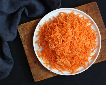 raw grated carrots on a plate, top view. fresh vegetables, food. copyspace. flat lay.の写真素材