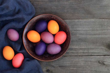 colorful Easter eggs in a clay bowl on the table.の写真素材
