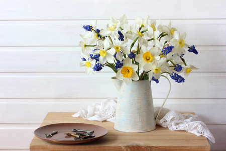 white daffodils with a yellow center and blue muscari in a jugの写真素材