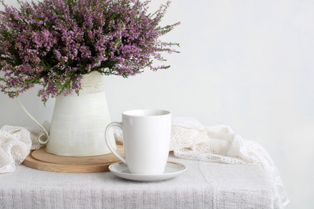 White mug and heather flowers in a vintage pitcher creating a cozy home atmosphereの写真素材
