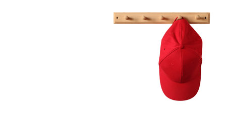 A red baseball cap hangs on a wooden clothes rack, isolated on a white background and a copy space.の写真素材
