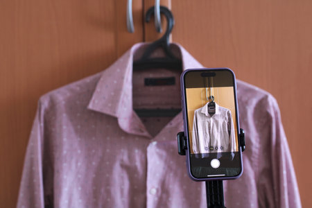 Online seller taking photos of clothes for sale on an e-commerce platform. online resale,...