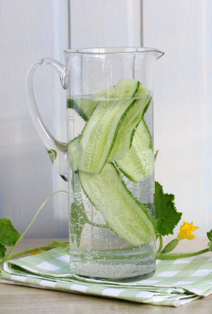 Cucumber water with bubbles in glass pitcher on checkered napkin, promoting healthy lifestyleの写真素材