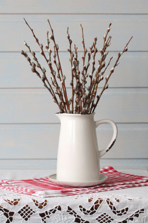 Pussy willow branches are arranged in a white pitcher, adding a touch of spring to a table settingの写真素材