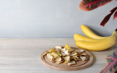 Chopped banana peels are displayed on a wooden board, next to fresh bananas, showcasing potential uses for composting or other purposesの写真素材