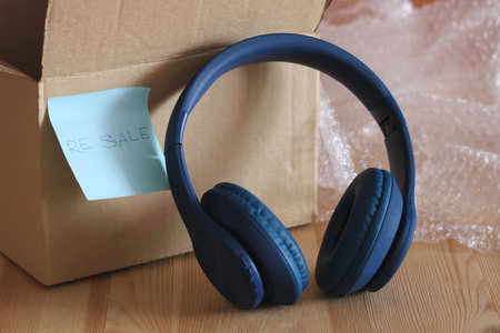 Wireless headphones next to cardboard box with resale label and bubble wrap