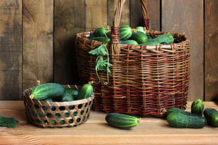 Freshly picked cucumbers overflowing from wicker baskets on a rustic wooden table, creating a charming still lifeの写真素材