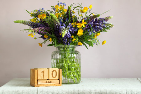 Wildflowers in glass vase next to wooden calendar showing June 10th