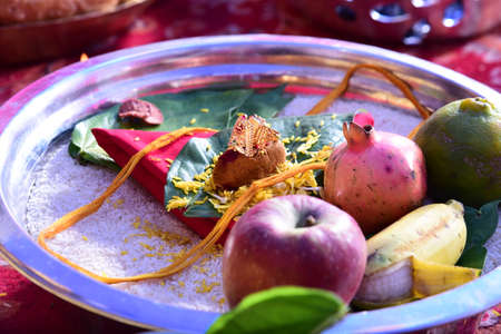 Plate full of fruits along with gold ring on green leafの写真素材