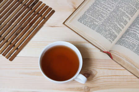 A Cup of tea and an old book on a wooden table.の写真素材