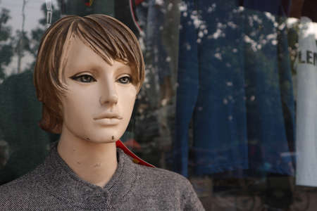 A sad, worn-out old mannequin stands by the window. Young plastic boy.の写真素材