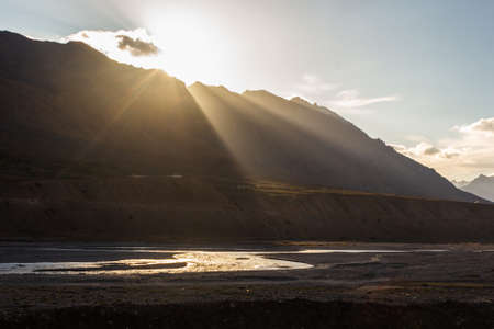 Sunlight hits the Spiti river winding through the mountains in the village of Kaza in Himachal...
