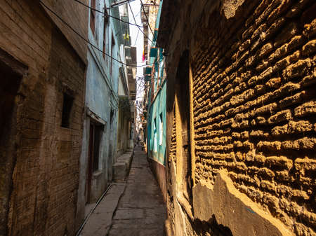 Varanasi, Uttar Pradesh, India - February 2015: A narrow alley going past the brick wall of a dilapidated house in the old city.のeditorial素材