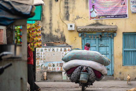 Somnath, Gujarat, India - December 2018:  A man on a motorcycle carrying big sacks of laundry past...