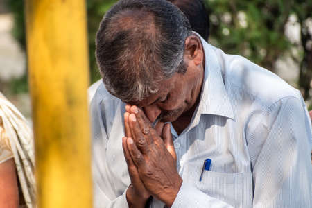 Nagpur, Maharashtra, India - March 2019; A candid portrait of a middle aged Indian man praying at a Buddhist temple with his hands folded.のeditorial素材