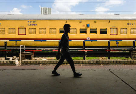 Bangalore, Karnataka, India - January 2020: A passenger walks on a platform in front of a yellow...