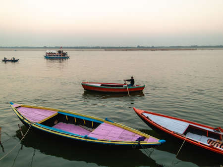 Varanasi, Uttar Pradesh, India - February 2015: COlourful scene with wooden rowboats on the Ganga river by the old ghats of the ancient city.のeditorial素材