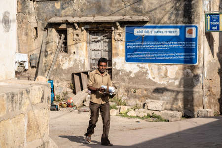 Somnath, Gujarat, India - December 2018:  An Indian man walks with a package on a sunny day in the...
