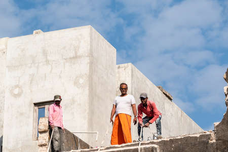Somnath, Gujarat, India - December 2018:  Three Indian men working on the plumbing on a rooftop of a...