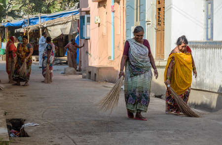 Somnath, Gujarat, India - December 2018:  Two Indian women wearing saris sweeping the streets of the town with broomsticks.のeditorial素材