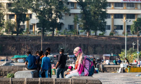 Nagpur, Maharahstra, India - March 2019: A young Indian girl wearing a veil sitting alone at the lakeside promenade of the Futala lake.のeditorial素材