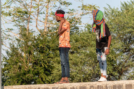 Nagpur, Maharahstra, India - March 2019: Two Indian boys standing on top of a wall and staring...
