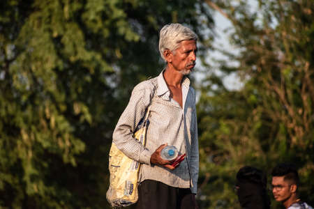 Nagpur, Maharahstra, India - March 2019: Candid portrait of an elderly Indian man walking with a...