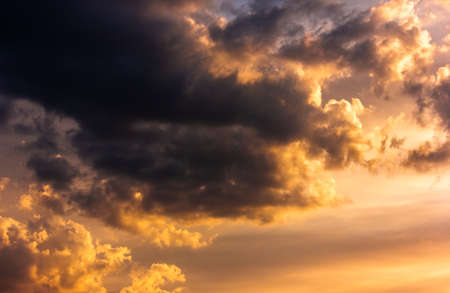 Dramatic dark clouds in the sky in orange sunset hues