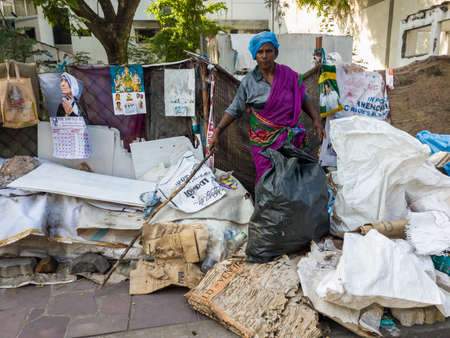 Pondicherry. India - February 2020: Indian woman sanitation worker cleaning trash on a roadside pavement in the city.のeditorial素材