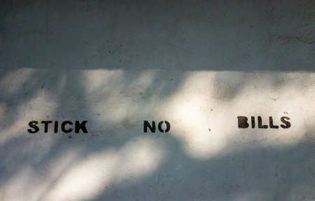 A Stick No Bills warning on a white wall in the city of Pondicherry in India.