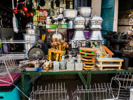 Trichy, Tamil Nadu, India - February 2020: Grinding stones, metal utensils,  non stick pans and assorted cookware in a roadside kitchenware store in a market in Tiruchirappalli.のeditorial素材