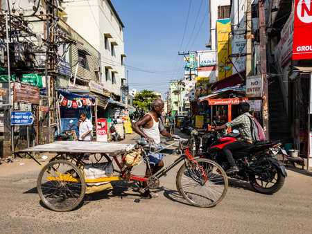 Trichy, Tamil Nadu, India - February 2020: An elderly Indian labourer walking with his wheeled cart...