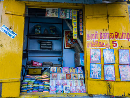 Trichy, Tamil Nadu, India - February 2020: A shop selling colorful ground rice kolam powder and framed images of Hindu Gods.のeditorial素材