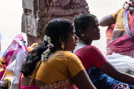Mayiladuthurai,  Tamil Nadu, India - February 2020: A candid portrait of an Indian woman dressed in a sari sitting inside a hall in the ancient Hindu temple of Vaitheeswaran Koil.のeditorial素材